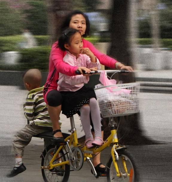 一位中国母亲载着她的两个女儿，没有戴头盔。